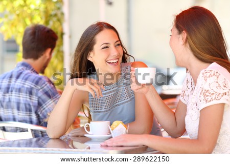 Two friends or sisters talking taking a conversation in a coffee shop terrace looking each other Royalty-Free Stock Photo #289622150