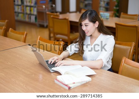 Asian beautiful female student study in library with laptop