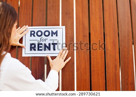 woman putting a sight "Room for rent on a wall"