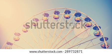 Retro vintage filtered picture of a carousel at sunset, summer fun concept background with lens flare effect.