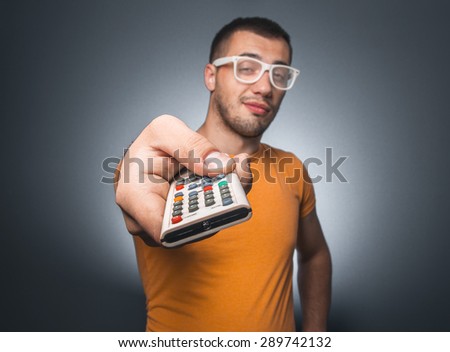 Man with remote control isolated on dark gray background. Guy holding controler, front view. TV - movies watching