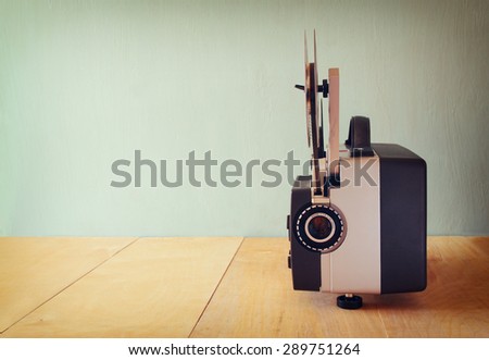 old 8mm Film Projector over wooden table and textured background
