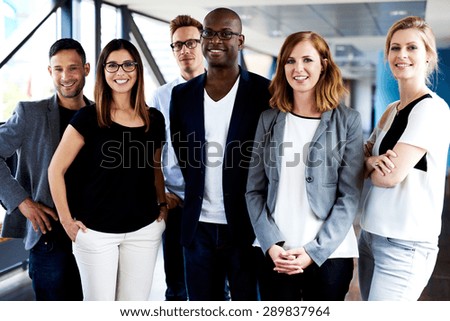 Group of young executives standing, smiling at camera and posing for picture