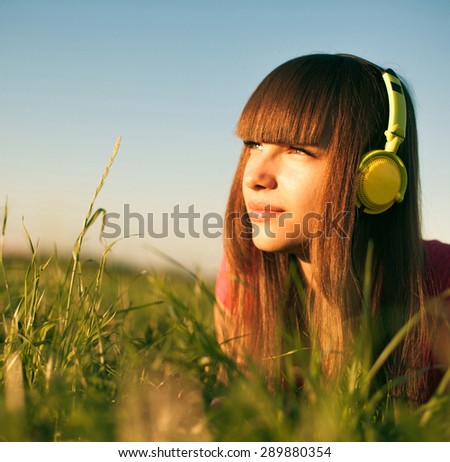 Beautiful Young Woman with Headphones Outdoors. Enjoy Music
