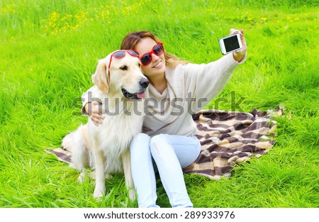 Owner woman with Golden Retriever dog taking selfie portrait on the smartphone in summer day