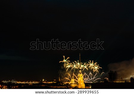 Fireworks over silhouette the city of St. Petersburg (Russia) on the feast of "Scarlet Sails" 2015, view from roof to silhouette of town with people. Peter and Paul Fortress and neva river 