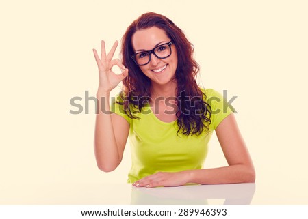 Smiling young woman gesturing ok, on a white background. Toned
