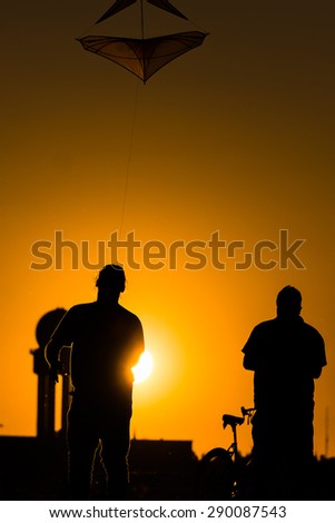 silhouettes flying a kite in sunset in berlin