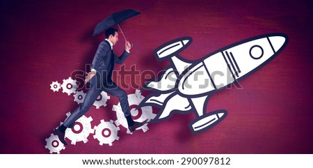 Businessman jumping holding an umbrella against desk