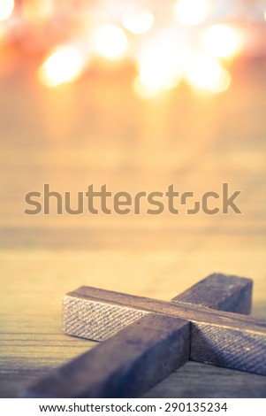 A wooden Christian cross laying on softly lit background. Room for copy.