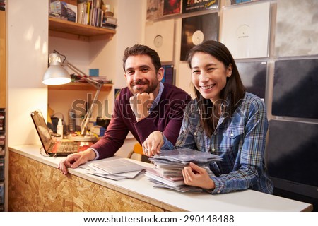 Man and woman working behind the counter at a record shop Royalty-Free Stock Photo #290148488