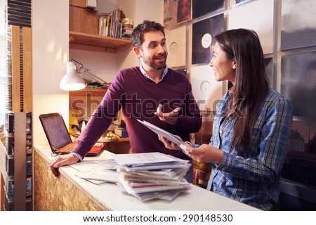 Man and woman working behind the counter at a record shop Royalty-Free Stock Photo #290148530