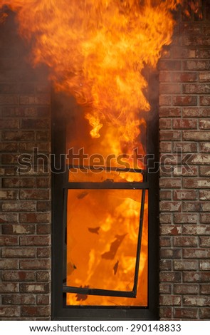 A house burns with flames shooting out the window.