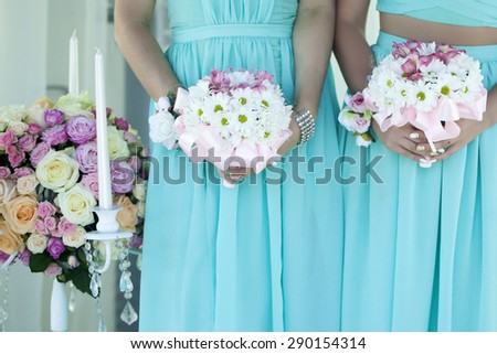 Two bridesmaids in light sky blue dressed holding soft white wedding bouquets standing on celebration background,  horizontal picture