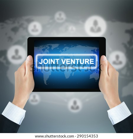 JOINT VENTURE sign on tablet pc screen held by businessman hands