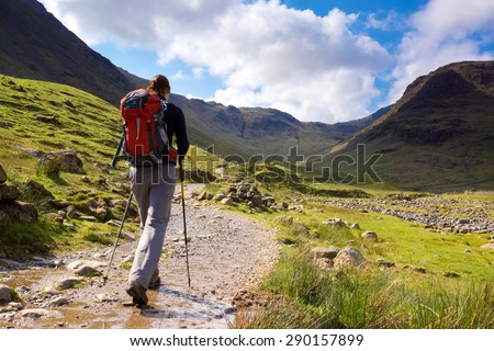 A walker approaches Seathwaite Fell in the Lake District, Cumbria, UK on a bright spring day. Royalty-Free Stock Photo #290157899