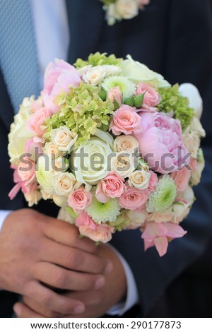 Fiance holding beautiful fresh wedding bunch of pink lilac purple white and violet chrysanthemum rose and peony flowers in hand closeup, vertical picture