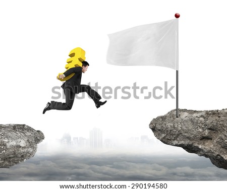 Jumping businessman carrying 3D golden dollar sign to white flag on cliff, with cityscape cloudscape background.