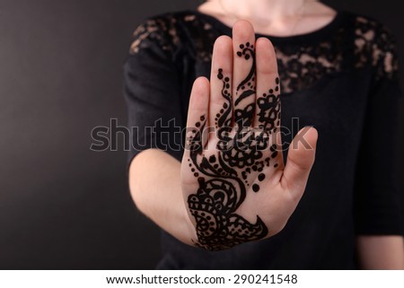 Closeup image of henna on female hand on dark background