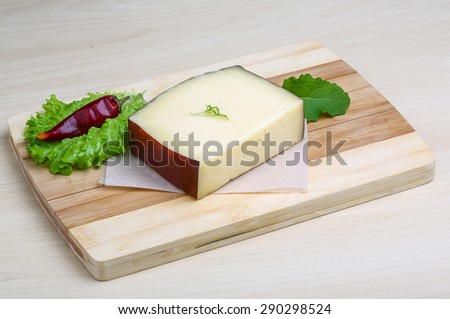 Hard cheese on the wood background with salad leaves