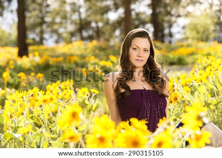 Young, attractive woman in a field of yellow flowers on a sunny day