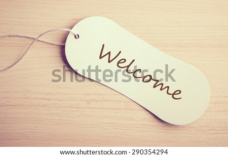 Welcome label is on the wooden desk background.