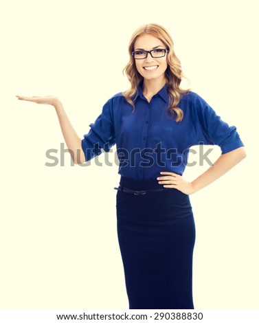 Cheerful beautiful young businesswoman in blue clothing showing something or blank copyspace area for slogan or text message