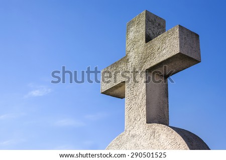 Stone cross against blue sky in a cemetery
