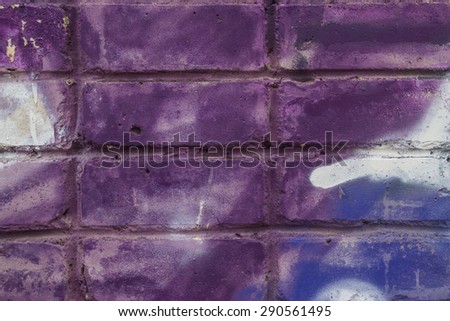 Painted brick wall with pastel violet graffiti