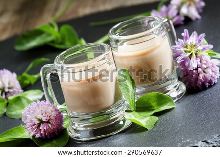 Coffee and Irish cream liqueur with flowers and clover shamrock in vintage mugs, selective focus