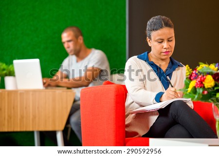 Young woman, taking notes and writing down ideasin a corporate lobby annex lounge on casual friday