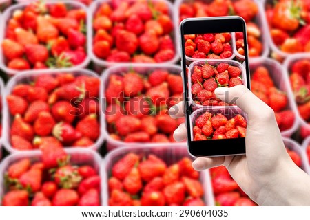 smartphone in hand and strawberries in the background