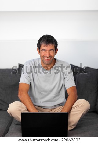 Man using laptop at home looking at camera