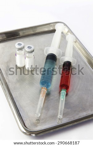 Vials and two syringe on stainless steel tray. On isolate.