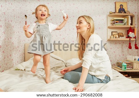 Mother and baby daughter plays at home on the sofa, room with icons