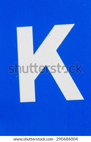 closeup white letter K from traffic road sign in thailand, on blue background