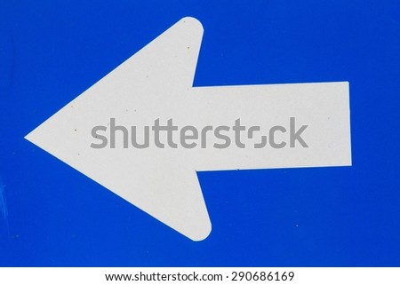 closeup blue road sign with white arrow to the left, background