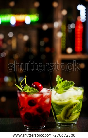 Glasses of cocktails in bar on bright blurred background