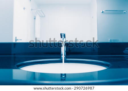 faucet with flowing water, blue tone