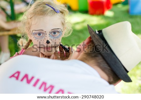 blond girl with facepainting and back view of animation team member