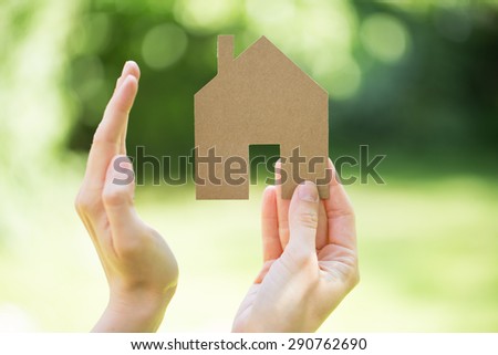 Hand protecting house cut of cardboard - ecoology concept