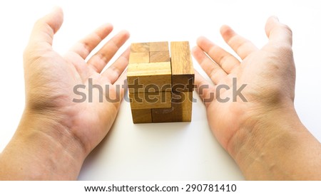 Hand holding piece of wooden block cube puzzle. Isolated on white background. Concept of complex and smart logical thinking. Slightly defocused and close up shot. Copy space.