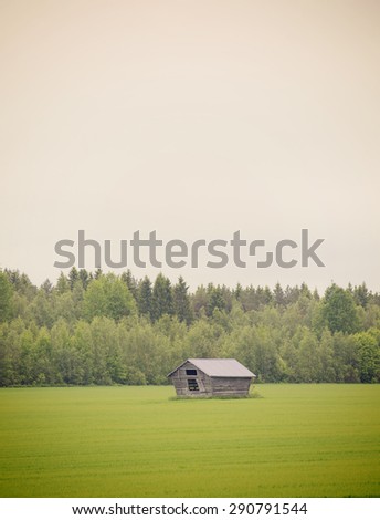 An old barn in the green field in the summer time. Image has a vintage effect.