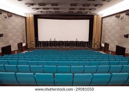 Empty cinema auditorium with line of green chairs and stage with silver screen. Ready for adding your own picture.