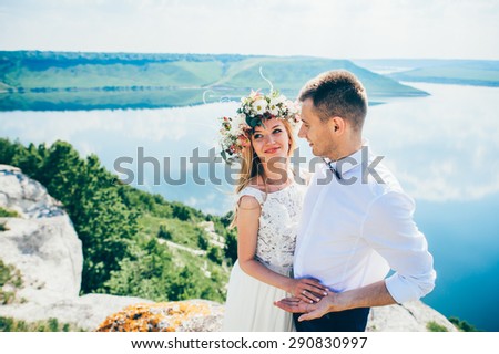 beautiful young couple posing on the rock near the lake 