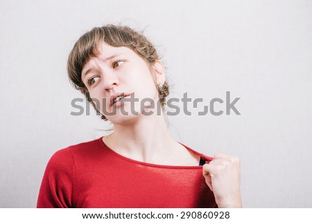 Woman pulls collar clothing. On a gray background. Royalty-Free Stock Photo #290860928