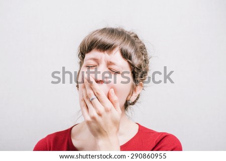 Woman yawning, sleepy. On a gray background. Royalty-Free Stock Photo #290860955