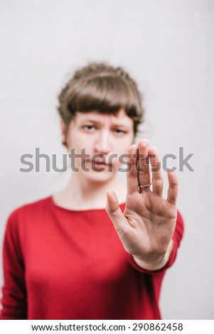 A woman shows a hand stop. On a gray background.