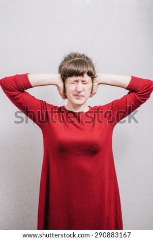 Woman covering her ears. On a gray background.