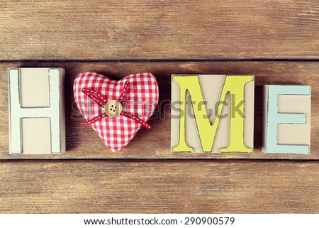 Decorative letters forming word HOME with decorative heart on wooden background